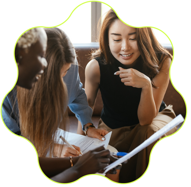 Three women sitting together and talking with papers in their hands. The photo is outlined with lime green squiggles.